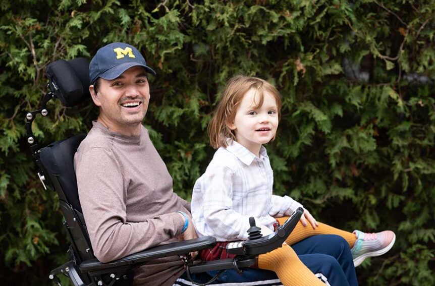 Brian Davis in his wheelchair and his daughter Ada on his lap.