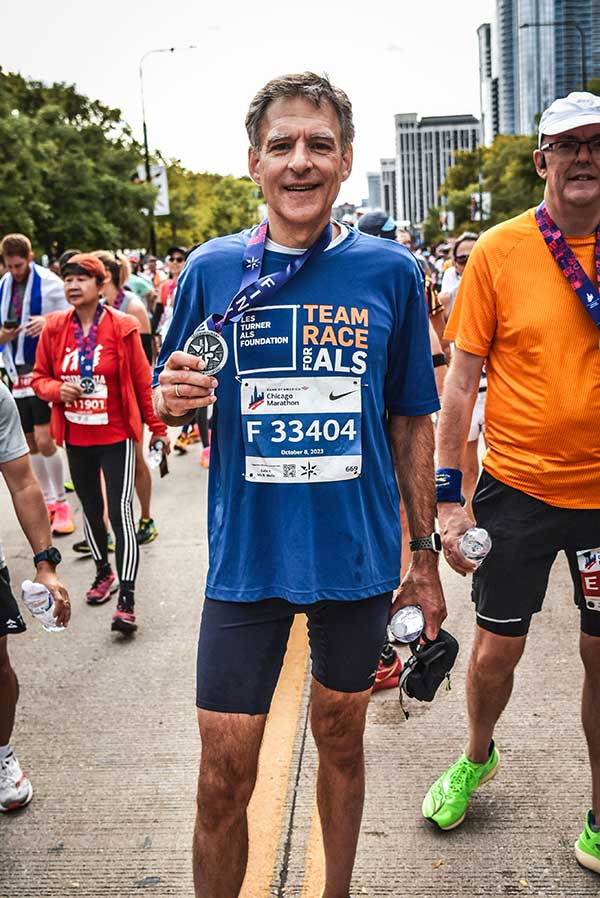 A Team Race for ALS runner holds his medal after finishing the Chicago Marathon